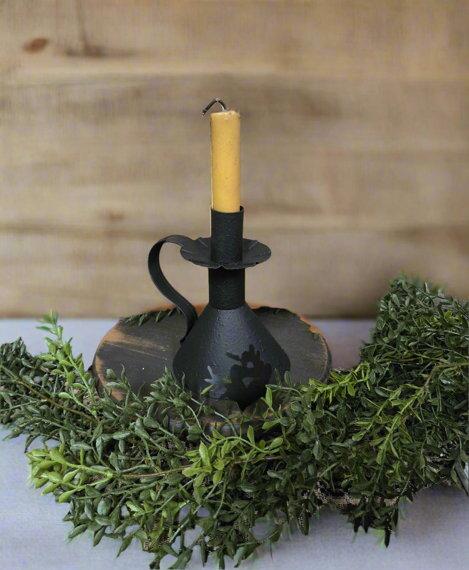 Textured black candle holder with handle and a cream colored taper with exposed wick