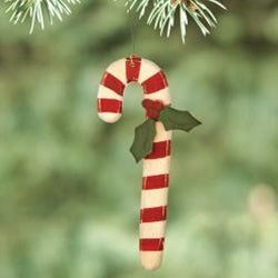 Candy cane ornament with red and white stripes hanging on a green branch.