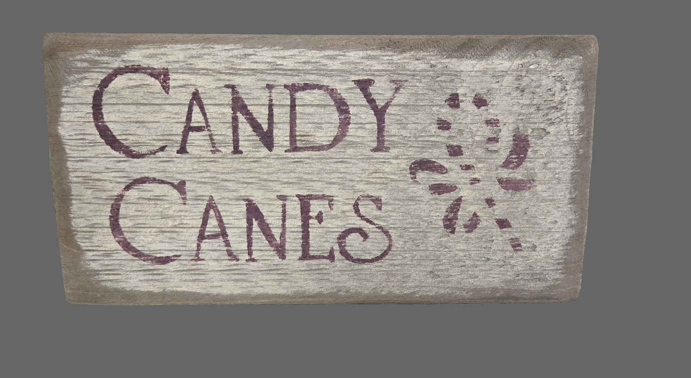 A wooden sign with the text 'Candy Canes' carved on it, featuring a pattern of candy canes in the background.