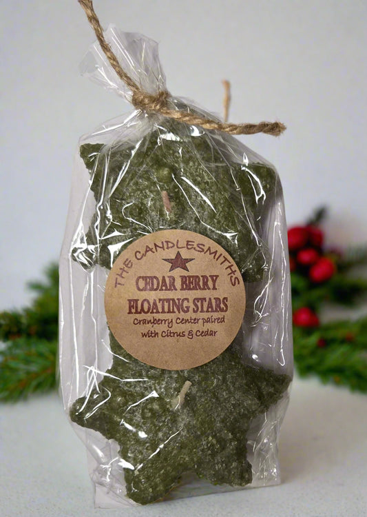 Two small star-shaped floating candles with a green tint, packaged in a clear plastic bag tied with twine at the top.
