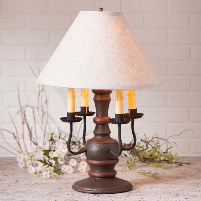 Decorative table lamp with a white lampshade on a wooden surface with a white brick wall background.