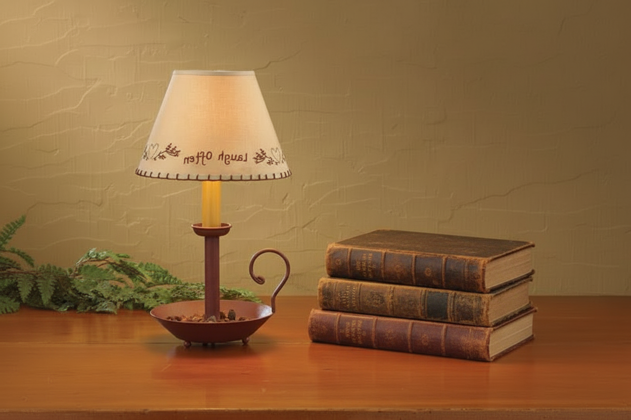 Small lamp with decorative shade on a wooden surface next to stacked books and a plant.