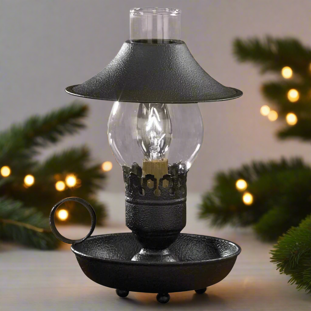 A black chamberstick lamp with an adjustable shade and a metal base, featuring a clear glass chimney and a black-colored lamp base.