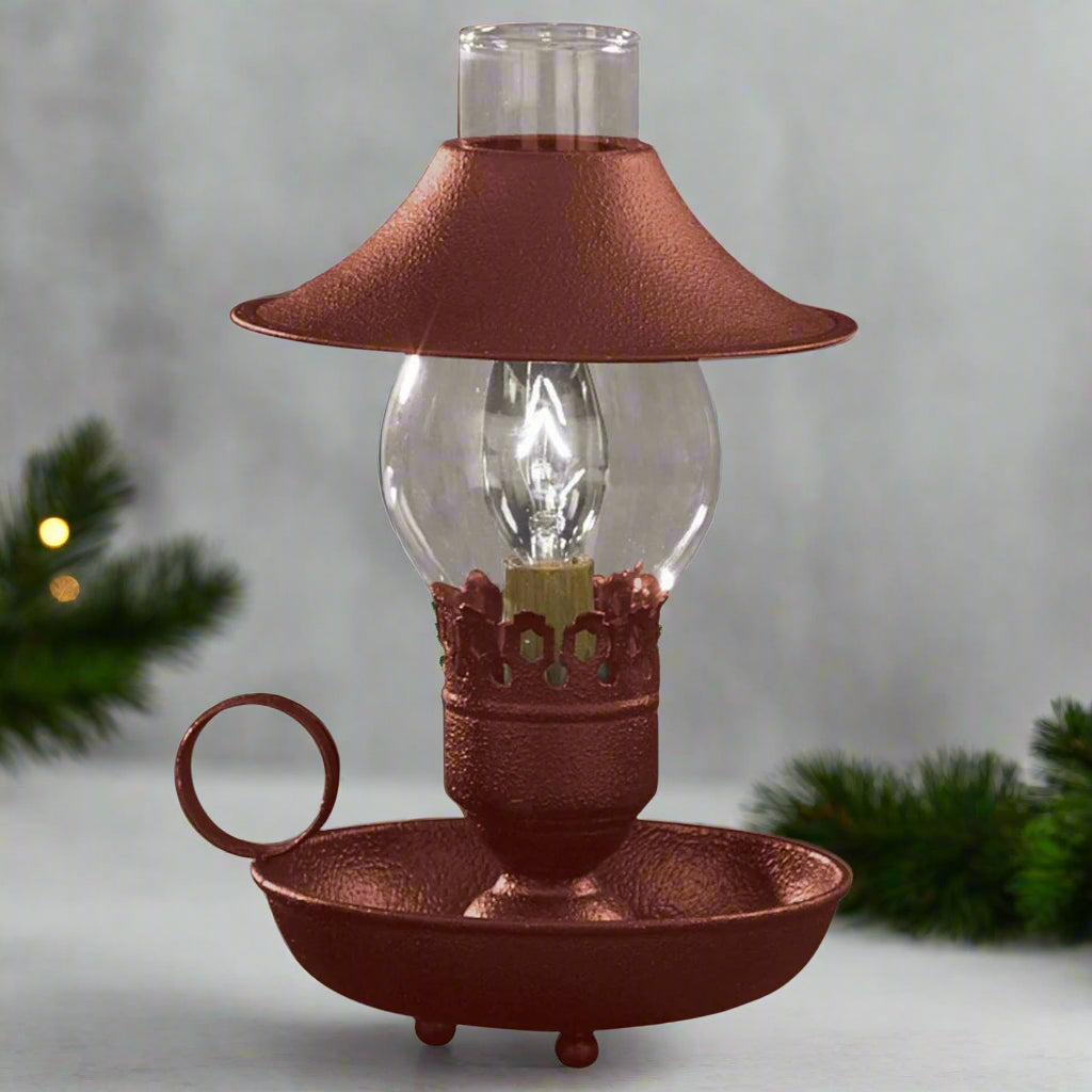 A red chamberstick lamp with an attached shade, featuring a bulb encased in a clear glass globe with a metal base and a brown matte finish.