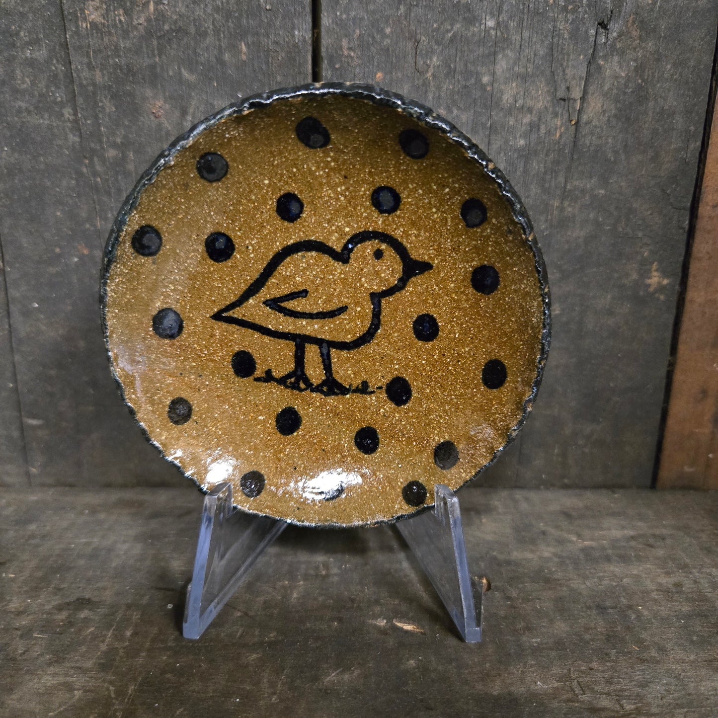 Round ceramic dish with black polka dots and a bird design on a wooden surface