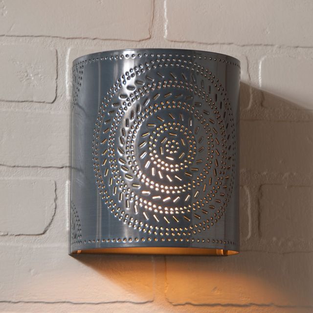 Decorative wall sconce with intricate cut-out design on a brick wall.