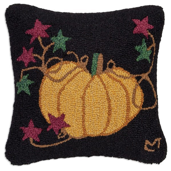 A rectangular hooked wool pillow with a black background featuring a hand-hooked design of a pumpkin and stars.