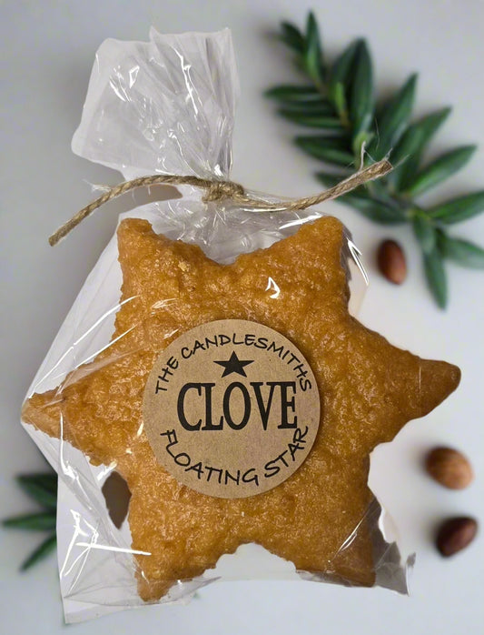 A star-shaped floating candle with a natural clove scent, packaged in clear wrapping with a label that reads 'CLOVE FLOATING STAR'.