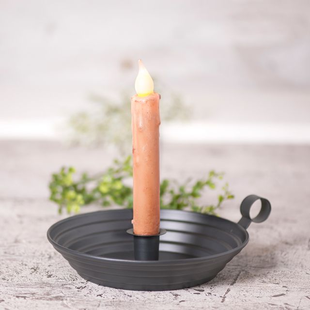 Colonial candle holder to hold a real or battery operated taper candle on wooden surface.
