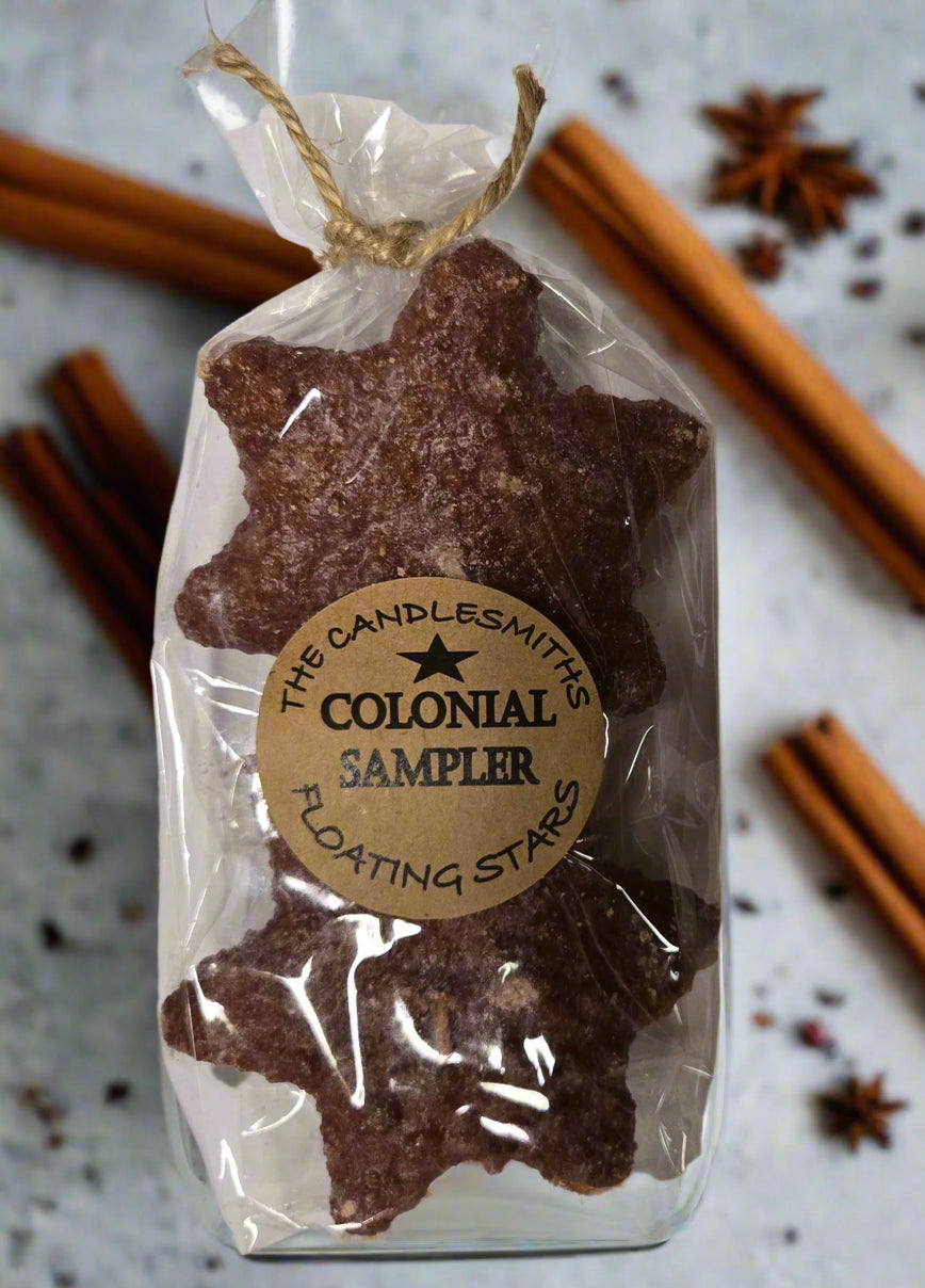 Two small star-shaped floating candles with a brownish tint, packaged in a clear bag with a label reading 'Colonial Sampler'.