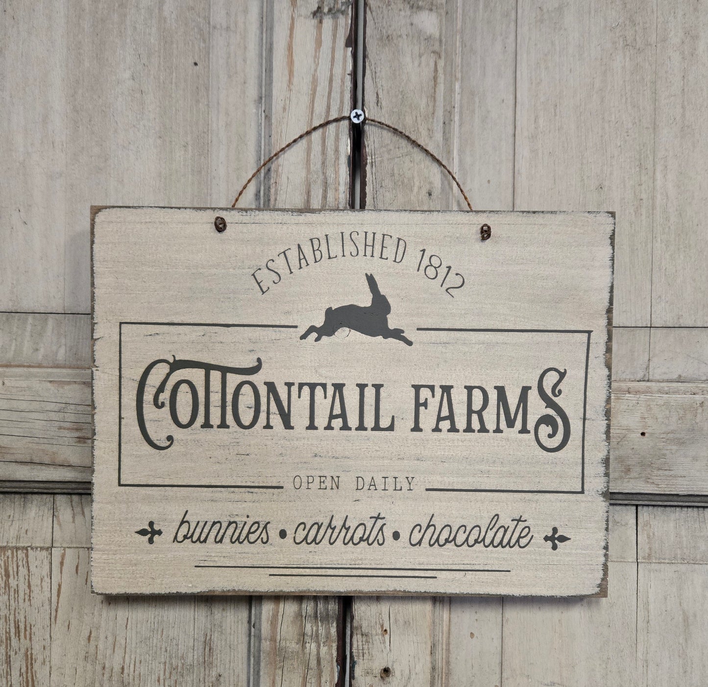 Wooden sign with 'Cottontail Farms' text and rabbit illustration on a wooden background