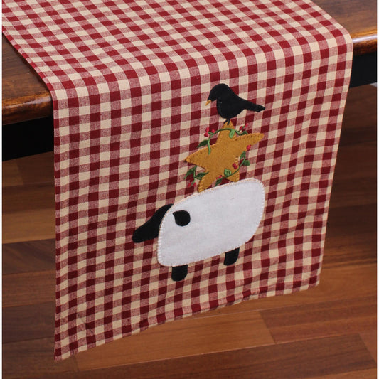 A red and white checkered table runner with a sheep and a bird applique design.