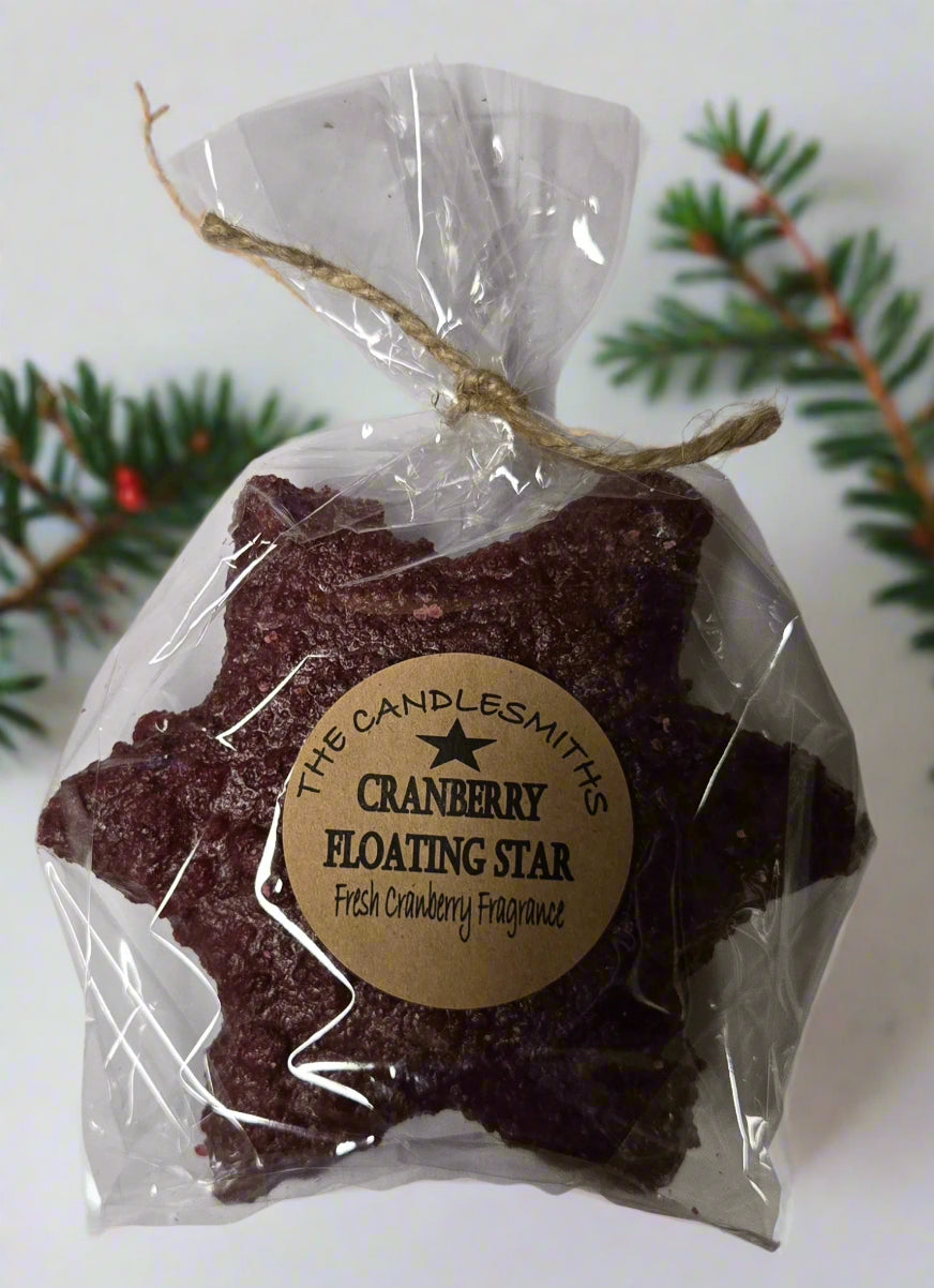 A cranberry-colored large star-shaped floating candle, packaged in clear wrapping with a label and a string tied to the top.