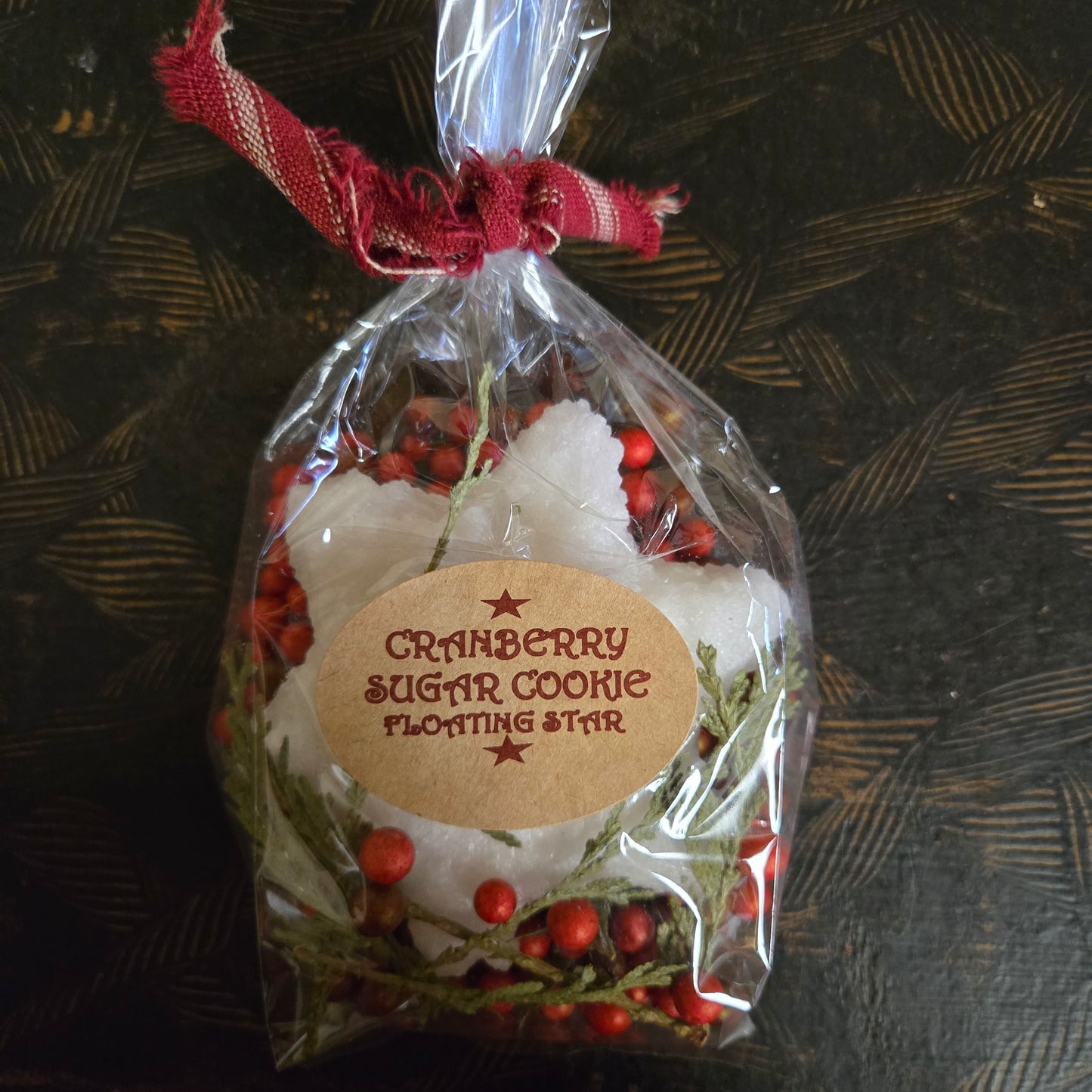 Packaged cranberry sugar cookie floating star with decorative label on a textured surface