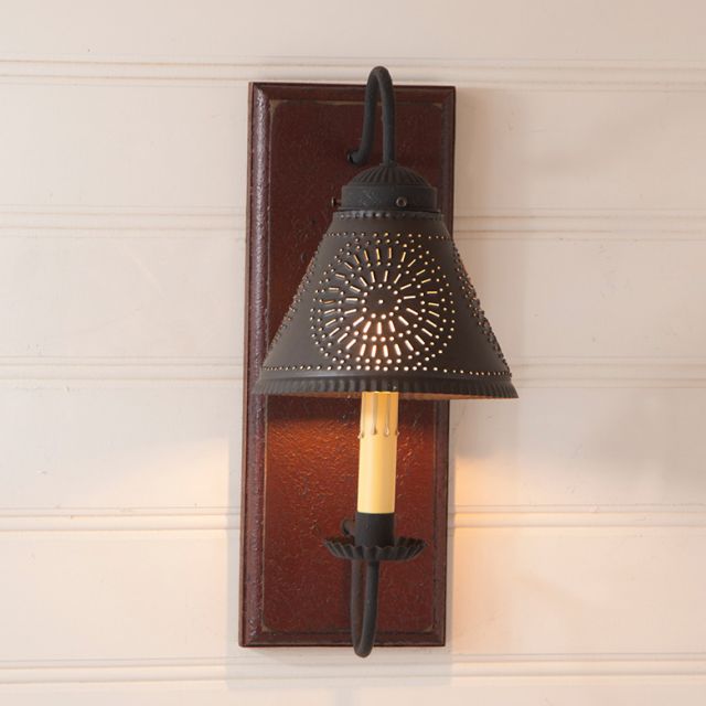 Decorative wall sconce with black metal shade and wooden base on a light-colored wall.