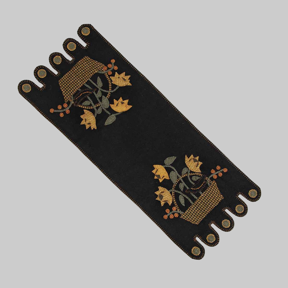 A black table runner with a whimsical crow in a basket design and fall leaves accents.