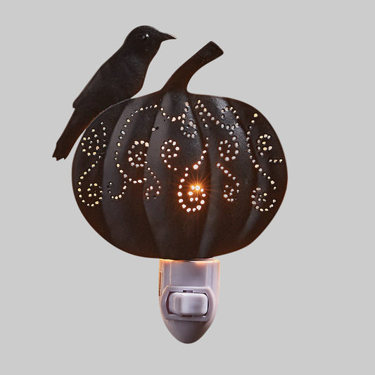 A night light featuring a carved pumpkin with a crow perched on top, with a warm glow emitting from the pumpkin.