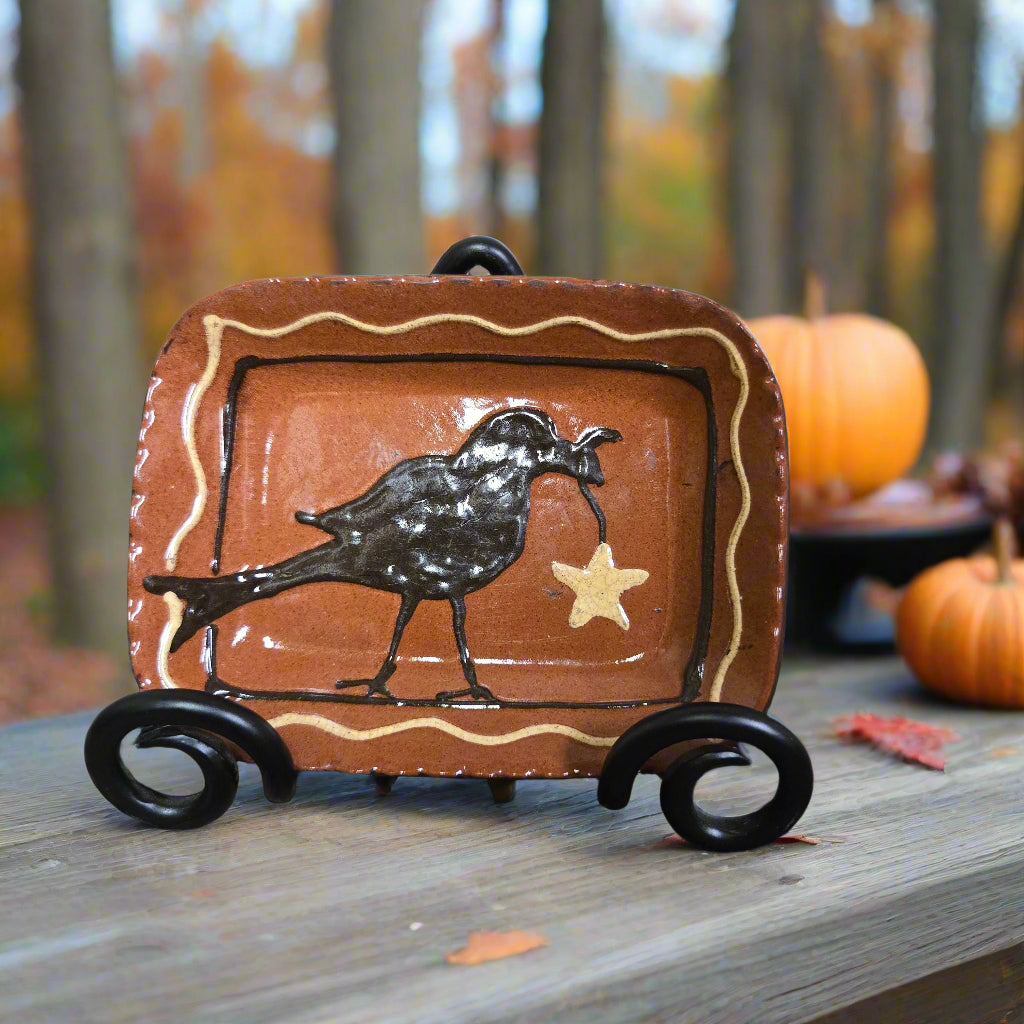 Ceramic tray with crow and star design on a textured surface