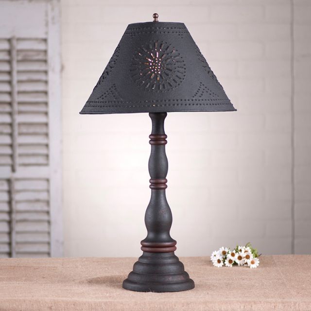 Decorative table lamp with a black pierced shade on a wooden surface.