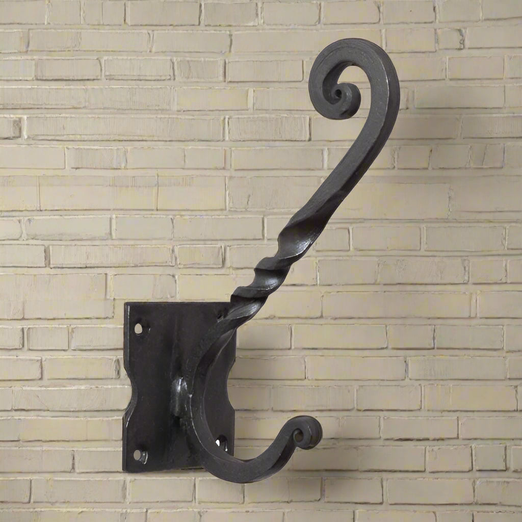 A traditional wrought iron wall hook with a decorative twist and curl design, in an antique black finish.