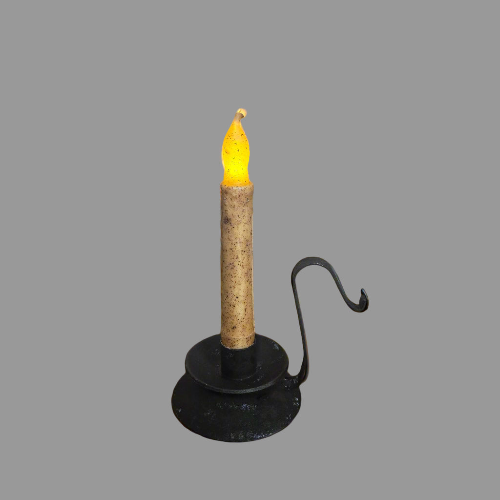 Decorative candle with cork base and black holder on a wooden surface with festive decorations.