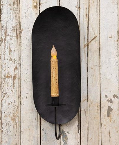 Iron sconce with battery operated taper displayed on rustic wood