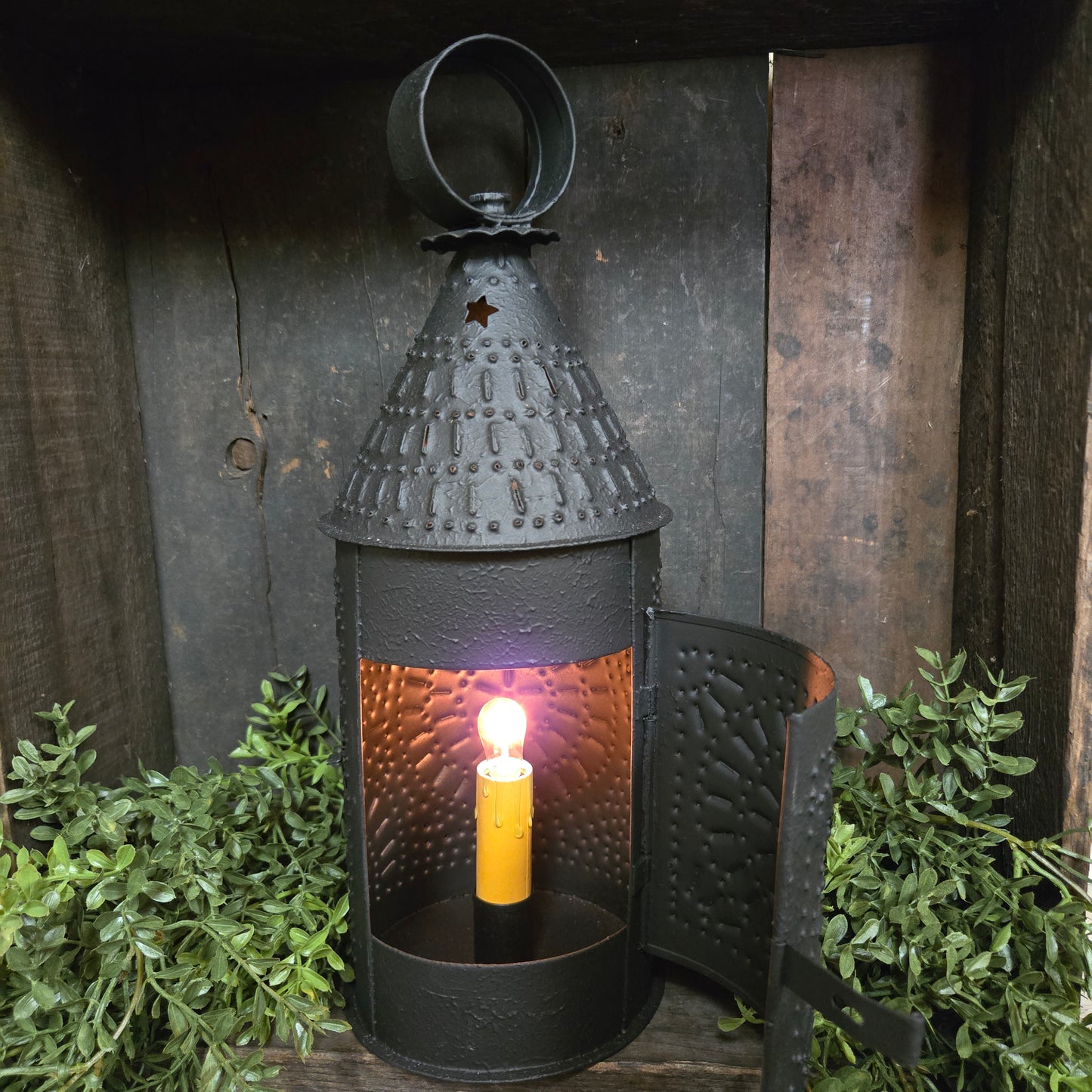 Decorative indoor light fixture on a wooden surface with greenery