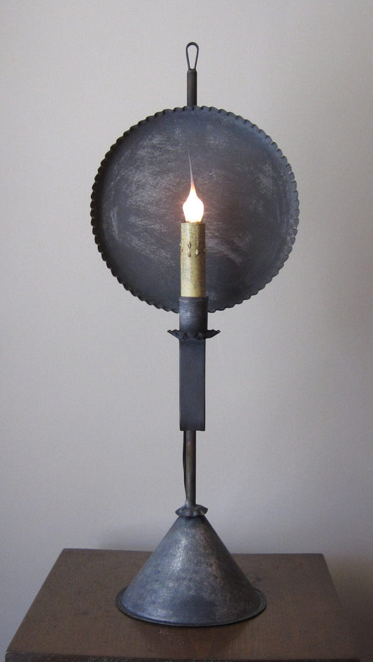 Decorative lamp with a round metal shade and visible flame on a plain background