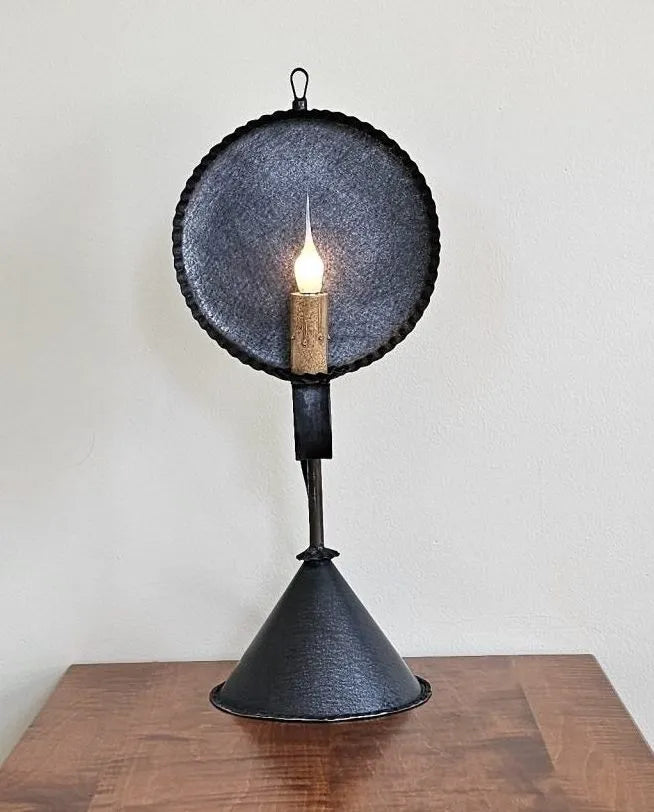 Black metal lamp with a light bulb on a wooden surface against a white wall