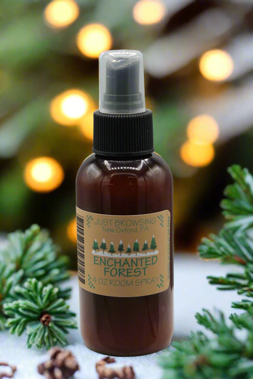 A 4oz bottle of Enchanted Forest room spray with a mist spray top. The bottle is brown with a label that has green text and a Christmas tree graphic, indicating a holiday-themed fragrance.