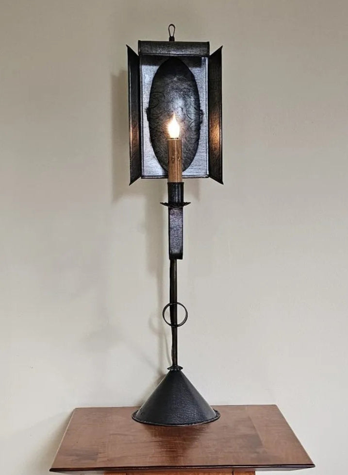 Decorative black lantern with a candle on a wooden surface against a plain wall.