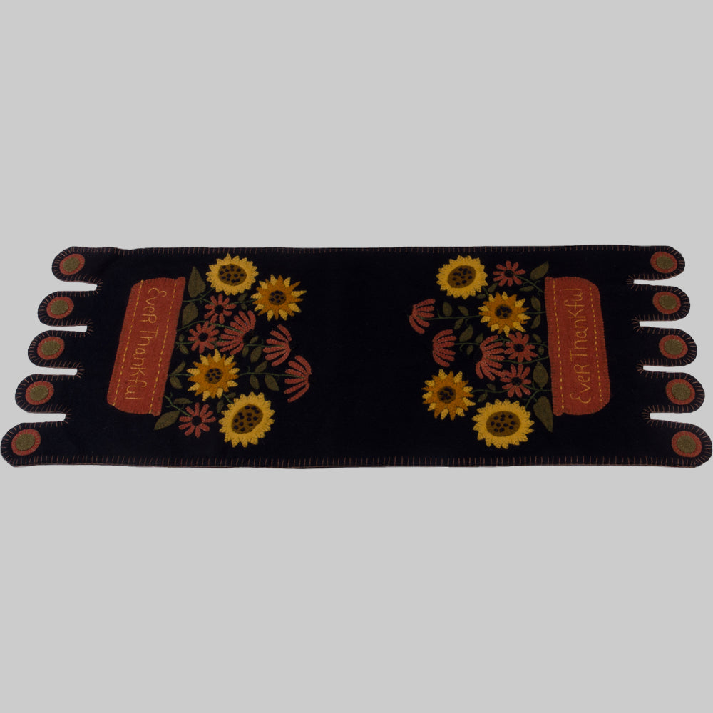 A black table runner with embroidered sunflowers and the text 'Ever Thankful' displayed across the center.