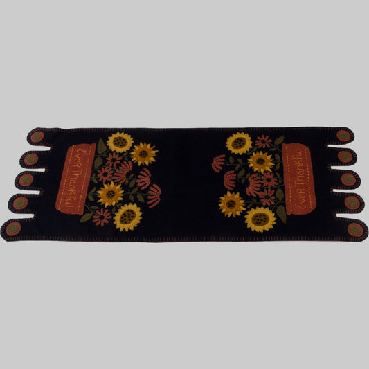 A black table runner with embroidered sunflowers and the text 'Ever Thankful' displayed across the center.