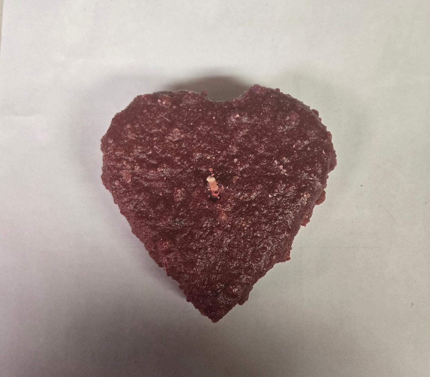 Heart-shaped object with a small insect on a light gray background