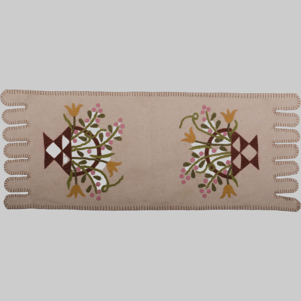 A cream-colored table runner with a floral basket design in the center, featuring embroidered details.