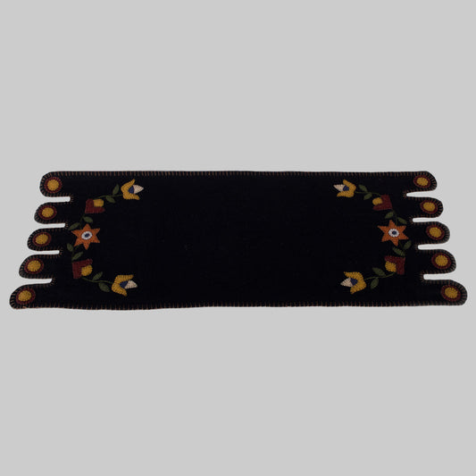 A black table runner with a floral design in the center, displayed on a neutral background.