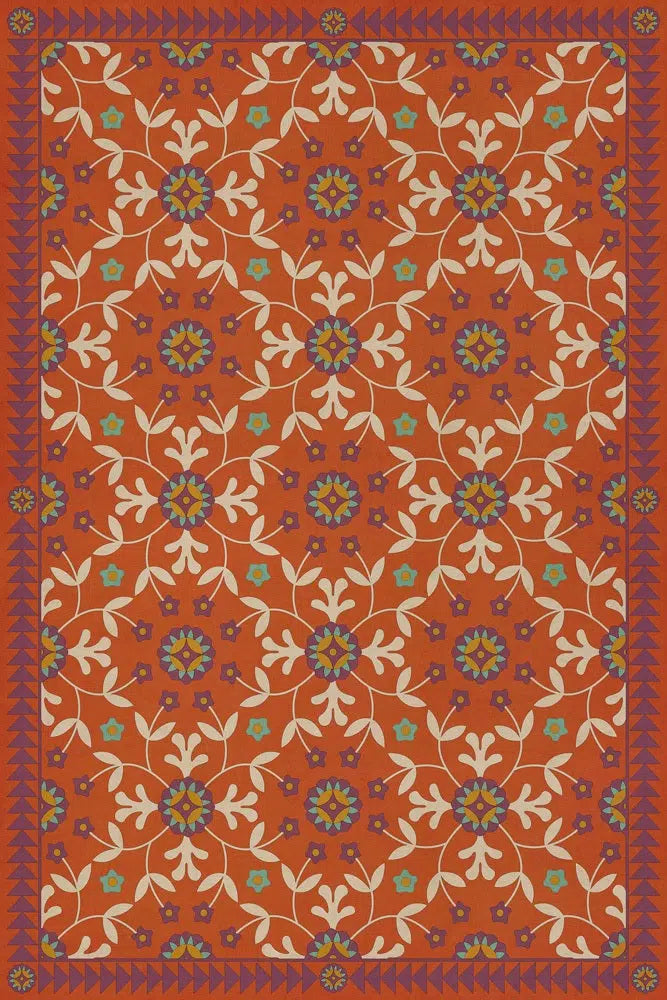 A rectangular floor cloth with a floral pattern in red, orange, and blue hues, featuring a geometric design.