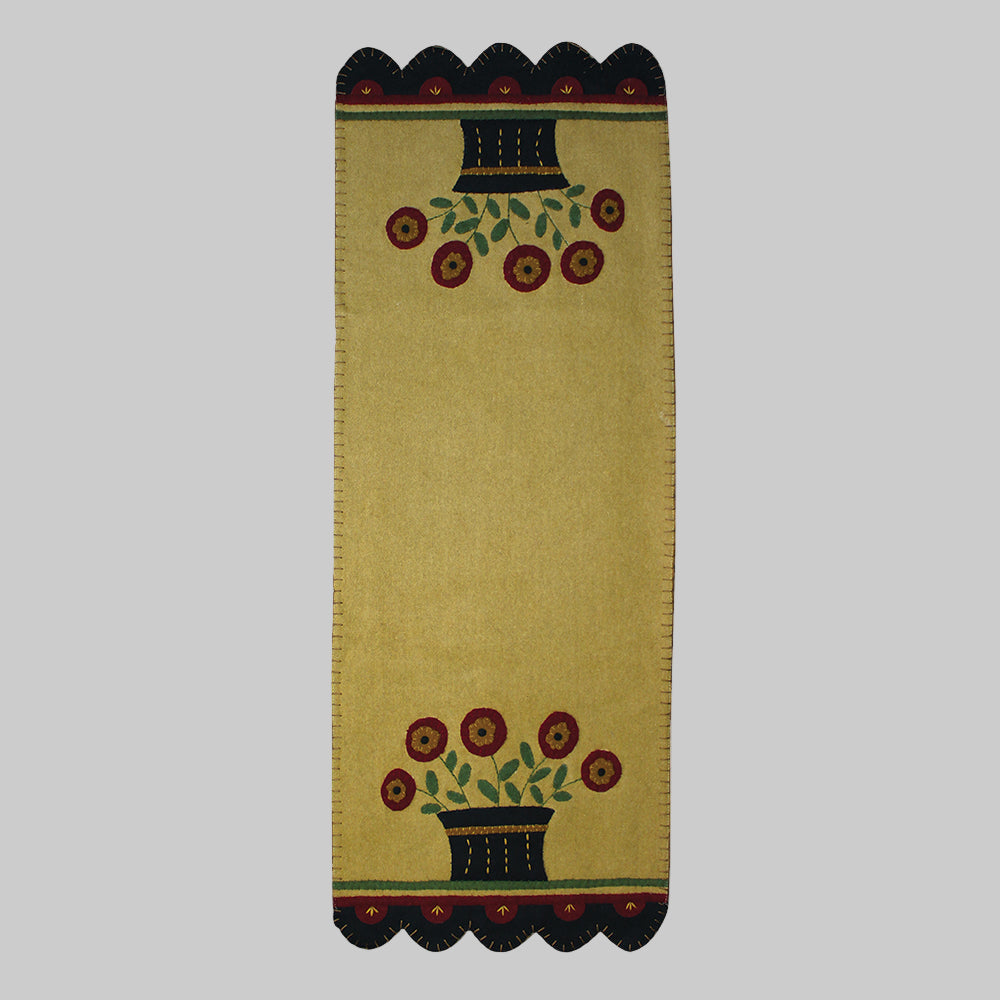 A beige table runner with a floral basket pattern and a dark, decorative border.