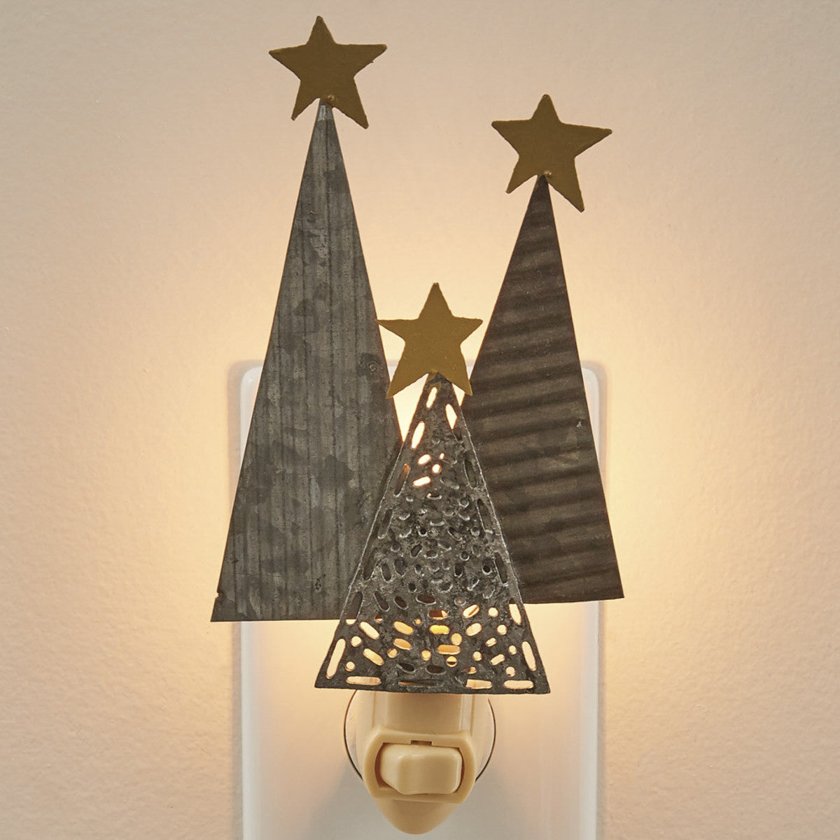 A wall-mounted night light featuring silhouettes of trees with star cut-outs in a warm gray color emitting a soft glow.