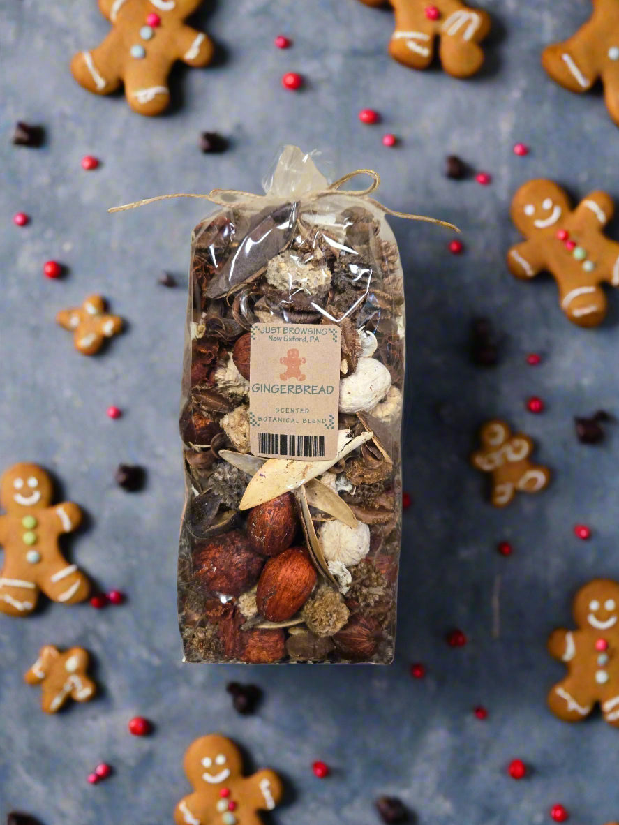 Packaged gingerbread spice mix with gingerbread cookies and spices on a dark surface