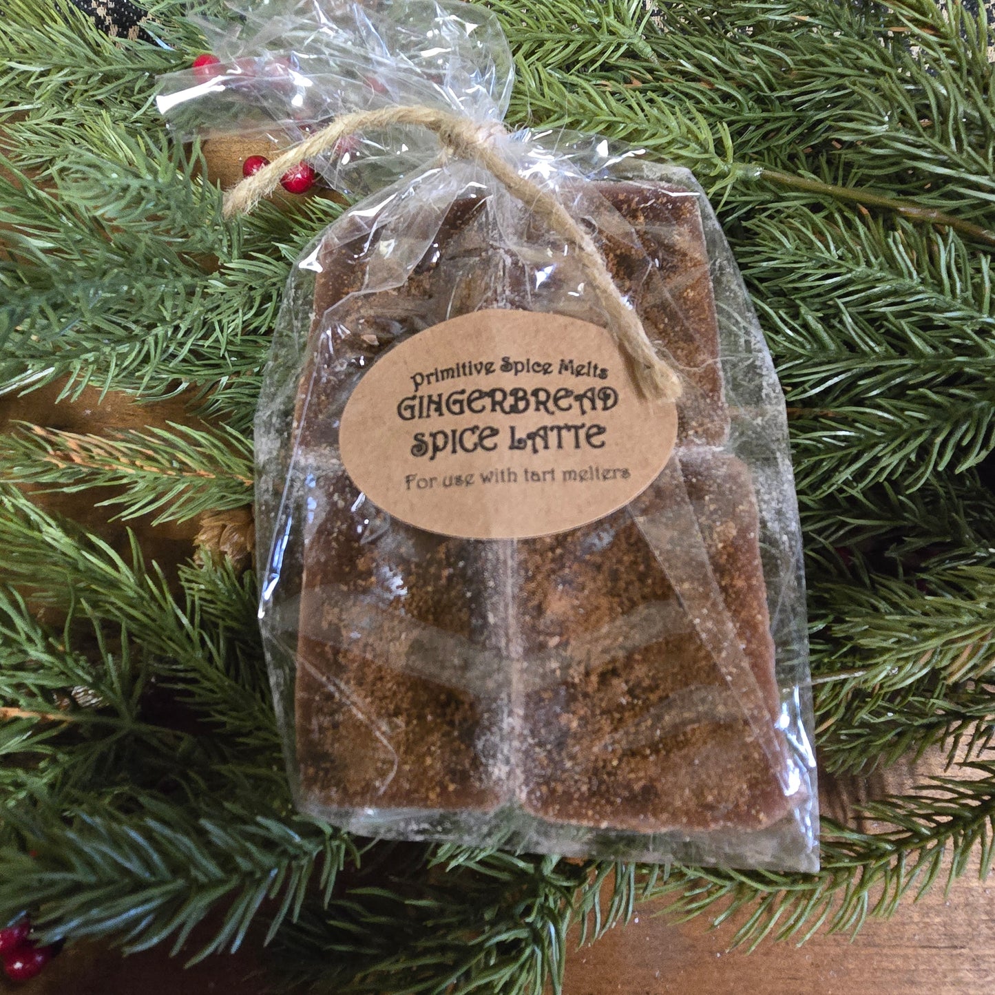 A pack of Gingerbread Spice Latte wax melts placed on a pine branch, with a label that reads 'Gingerbread Spice Latte' for use with essential oils.