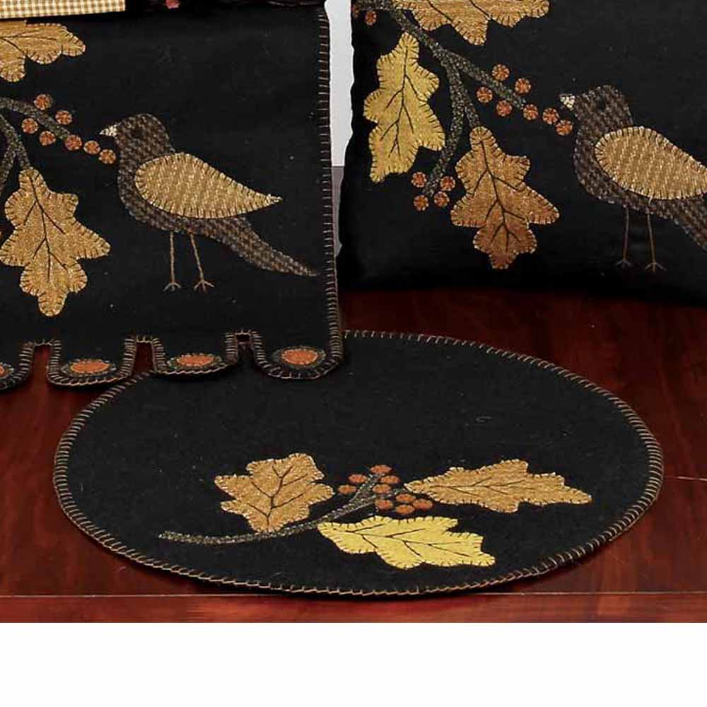 A set of two candle mats with a bird and leaf design, one mat is folded and the other is laid out, both with embroidered details.