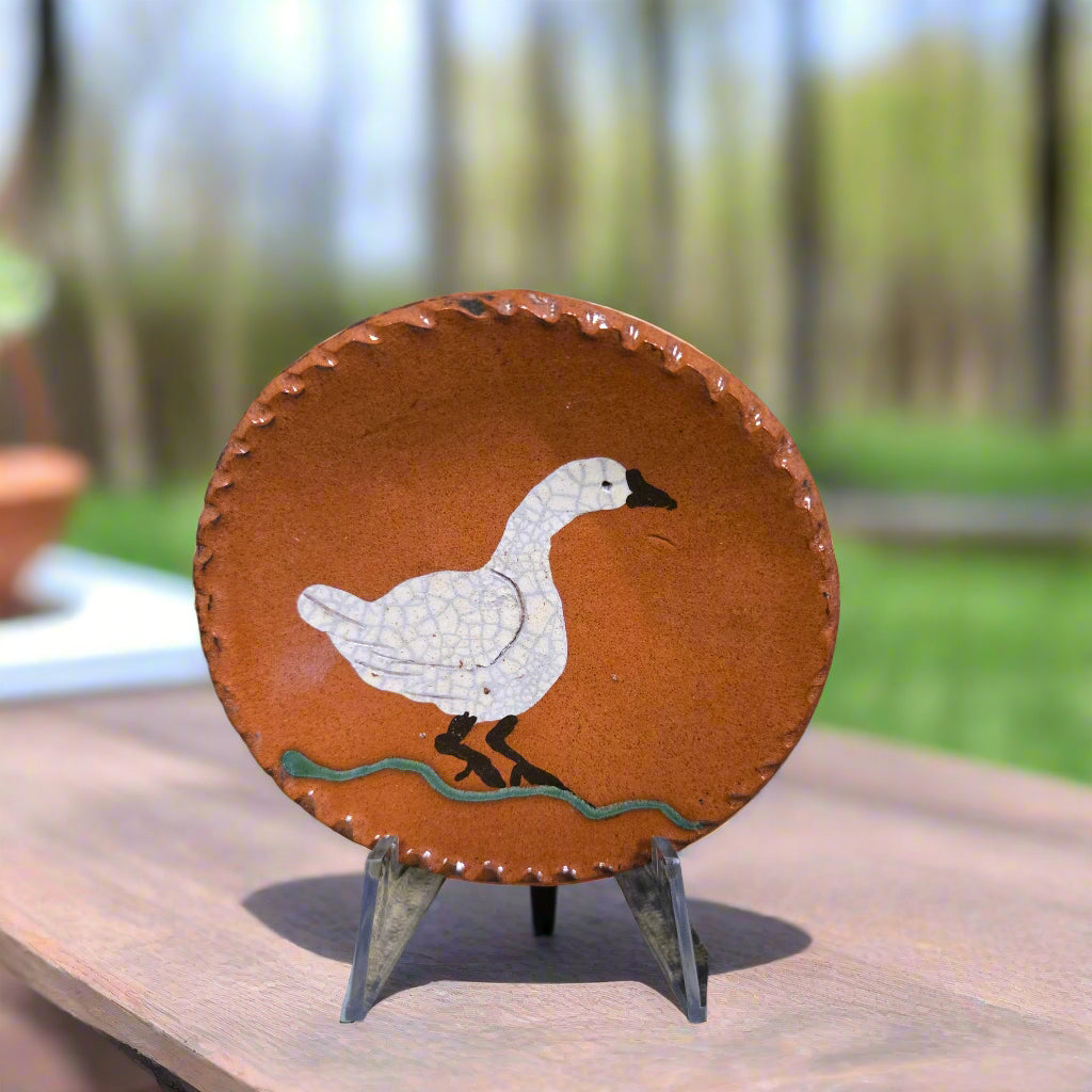 Small round redware plate with a goose glazed in a vibrant cream color