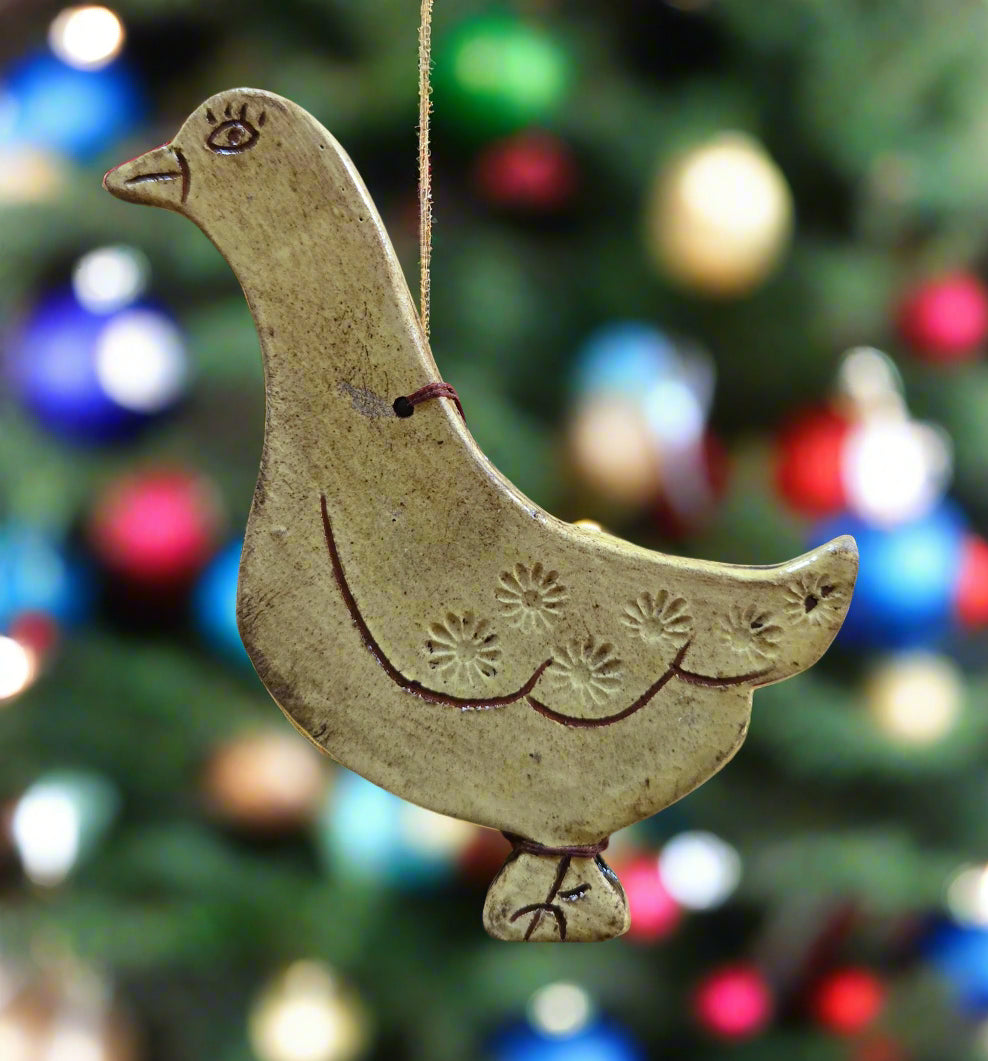 Decorative ceramic dove ornament against a blurred Christmas tree background with colorful lights.