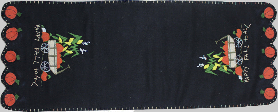 A black table runner with embroidered pumpkin and leaves design and the text 'Happy Fall to All'.