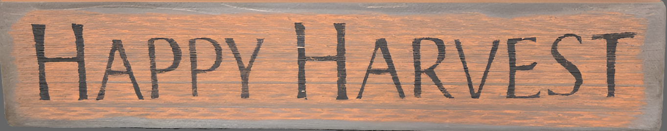 Pumpkin colored wood sign with the words "Happy Harvest" in black