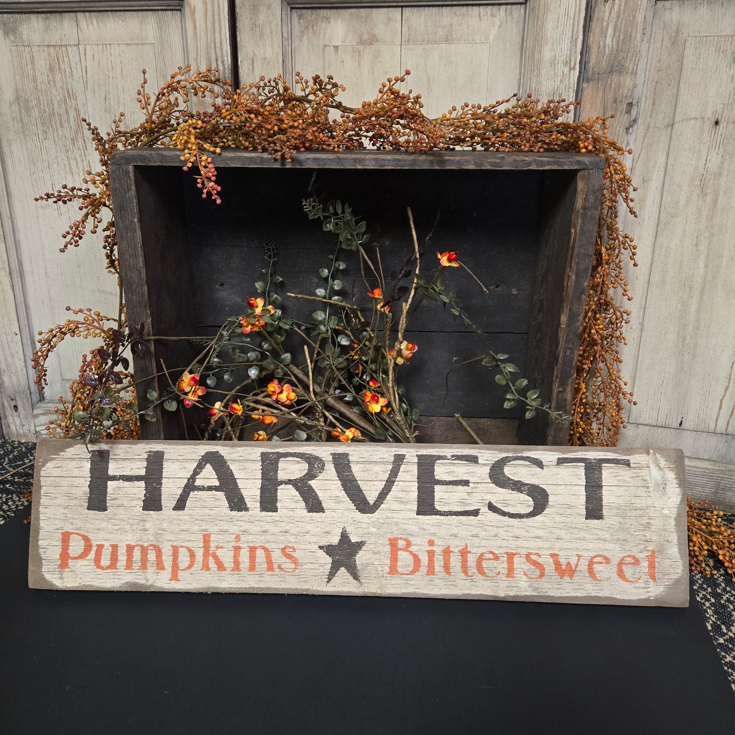 Decorative sign with 'Harvest Pumpkins Bittersweet' text next to a wooden box with autumnal decorations.