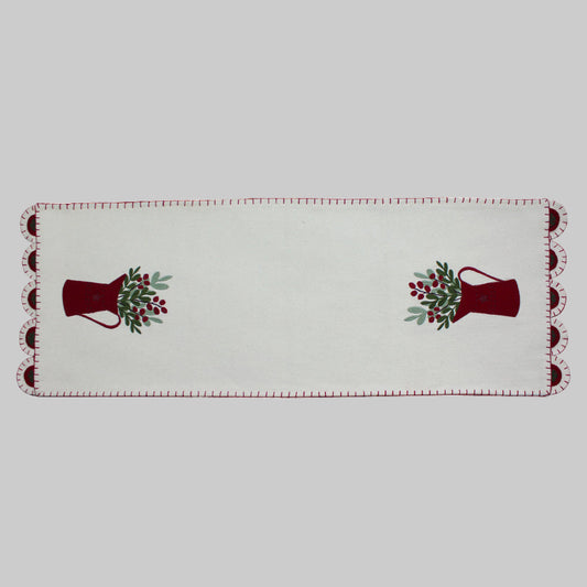 A cream-colored table runner with a pitcher design and red trim, suitable for holiday dining tables.