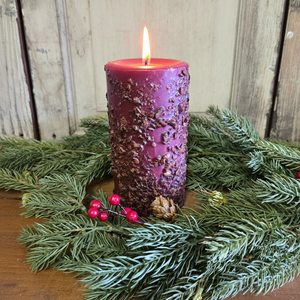 Purple textured candle on a bed of greenery with a wooden background