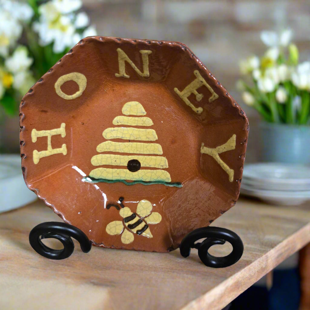 Decorative plate with 'HONEY' and a bee design on a stand.